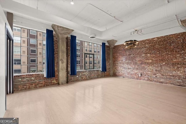 empty room with brick wall and wood finished floors