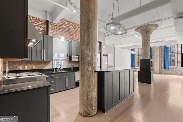 kitchen with appliances with stainless steel finishes, dark countertops, pendant lighting, and a sink