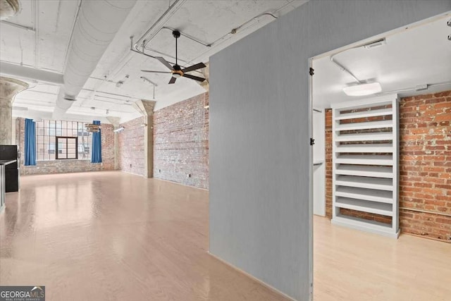 interior space featuring light wood finished floors, brick wall, and a ceiling fan