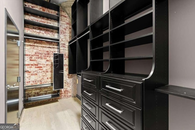 walk in closet with light wood-style floors