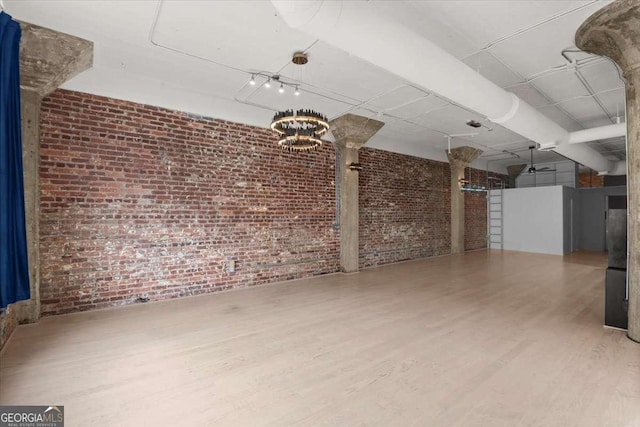 spare room featuring brick wall and wood finished floors