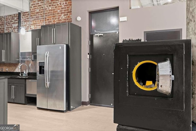 kitchen with dark countertops, light wood-style flooring, decorative light fixtures, gray cabinetry, and stainless steel refrigerator with ice dispenser