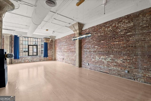 interior space with brick wall, wood finished floors, and visible vents