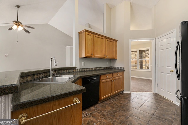 kitchen with high vaulted ceiling, a sink, brown cabinets, dark stone counters, and black appliances