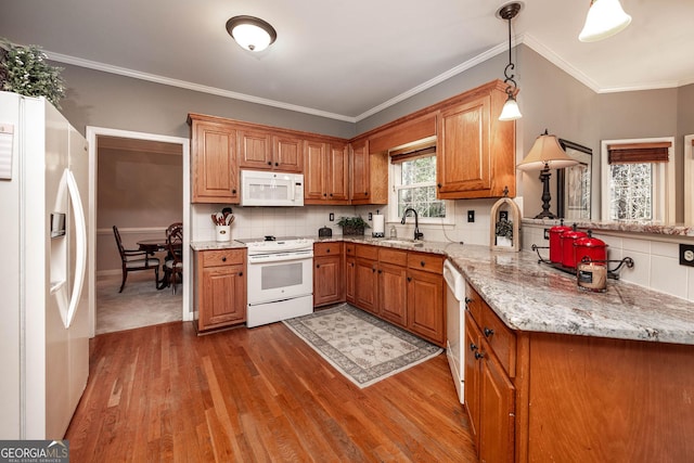 kitchen with hanging light fixtures, brown cabinetry, light stone countertops, white appliances, and a peninsula