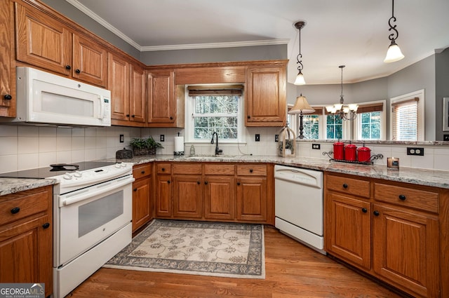 kitchen featuring pendant lighting, white appliances, a sink, and light stone countertops