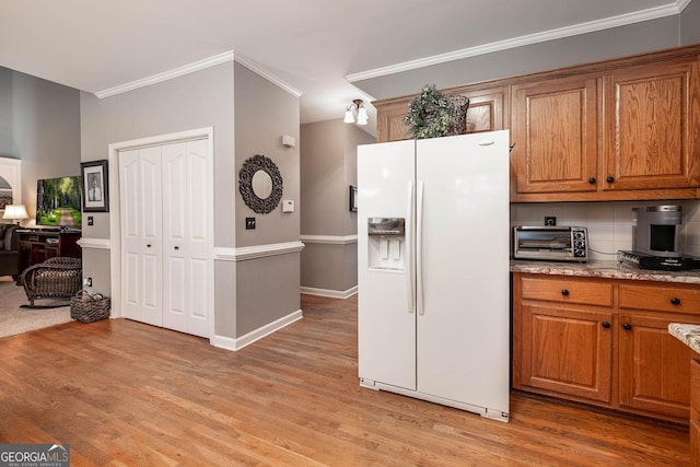 kitchen featuring a toaster, crown molding, light wood-style floors, white fridge with ice dispenser, and backsplash