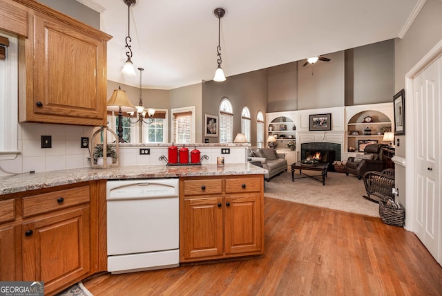 kitchen featuring dishwasher, open floor plan, hanging light fixtures, light stone countertops, and a fireplace