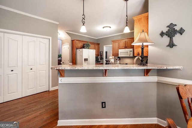 kitchen with dark wood-style floors, a breakfast bar area, hanging light fixtures, light stone countertops, and white appliances