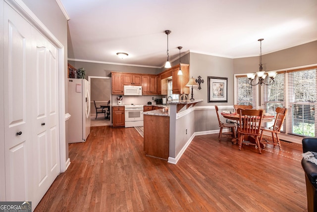 kitchen featuring white appliances, light stone counters, brown cabinets, a peninsula, and hanging light fixtures