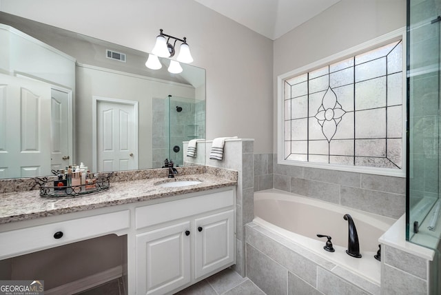 bathroom featuring visible vents, tiled shower, a bath, and vanity