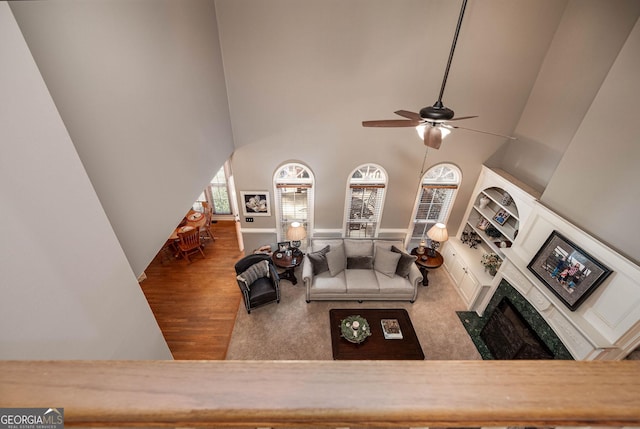 living room featuring dark wood-style floors, ceiling fan, and a high ceiling