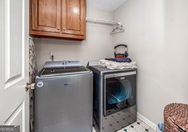 washroom with baseboards, cabinet space, and washer and dryer