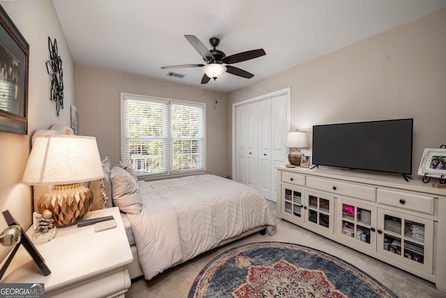 bedroom featuring light carpet, a ceiling fan, visible vents, and a closet