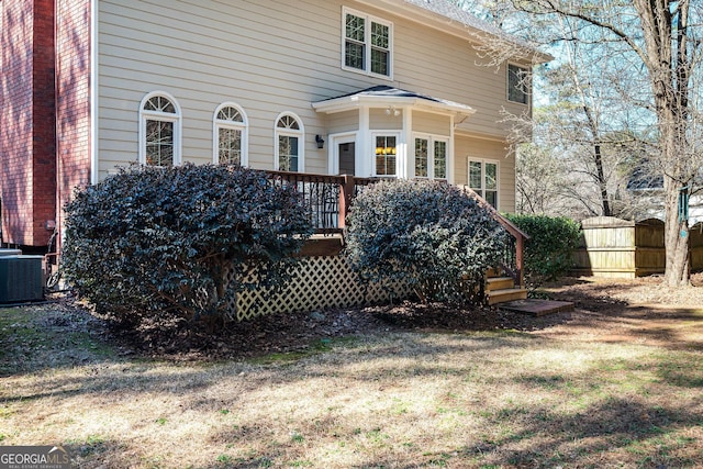 view of side of property featuring central air condition unit, fence, a deck, and a yard