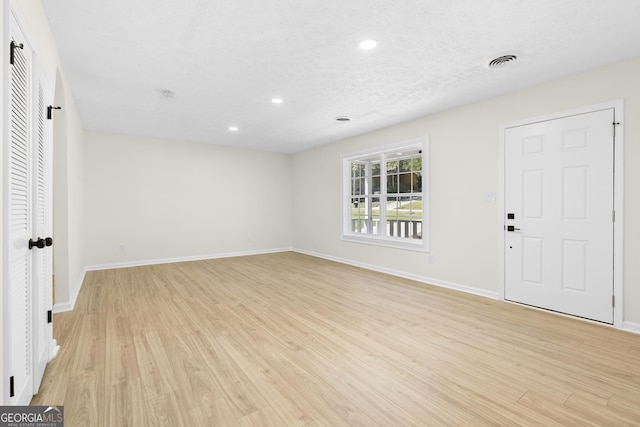 interior space featuring a textured ceiling, recessed lighting, visible vents, baseboards, and light wood finished floors