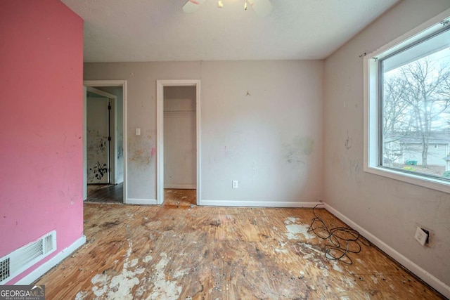 unfurnished bedroom featuring baseboards, multiple windows, visible vents, and a closet