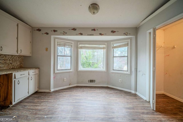 unfurnished dining area with visible vents, baseboards, and wood finished floors