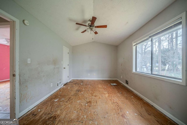 unfurnished room featuring visible vents, baseboards, lofted ceiling, ceiling fan, and wood finished floors