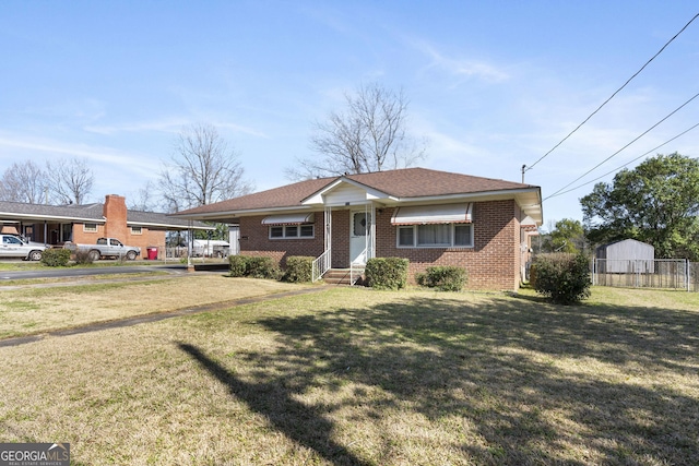 view of front of house with brick siding, a front lawn, fence, and an attached carport