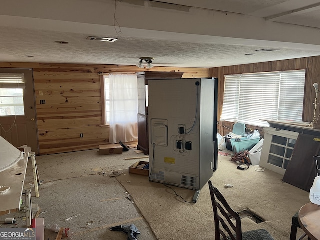 kitchen featuring fridge, wooden walls, and visible vents