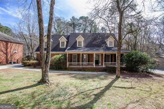 new england style home featuring covered porch, brick siding, and a front lawn