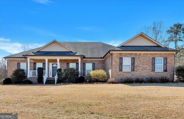 view of front of house with a porch, brick siding, a shingled roof, and a front lawn