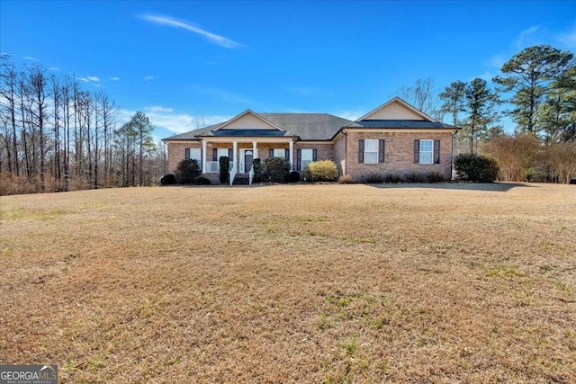 view of front of home featuring covered porch, brick siding, and a front yard