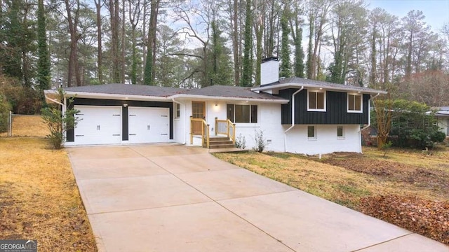 tri-level home with driveway, a chimney, and an attached garage