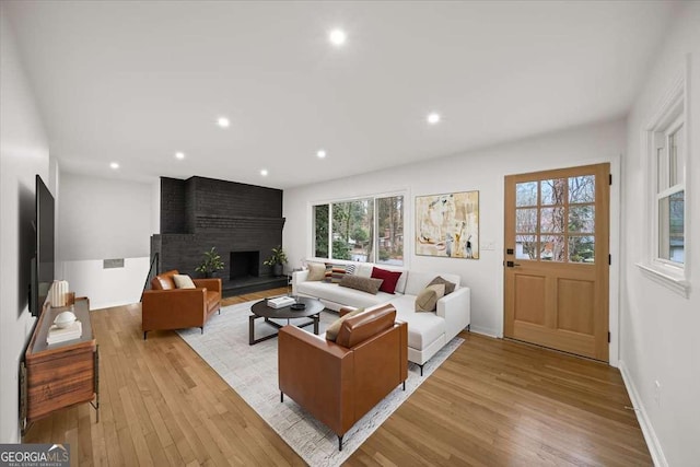 living area with light wood-style floors, recessed lighting, a fireplace, and baseboards