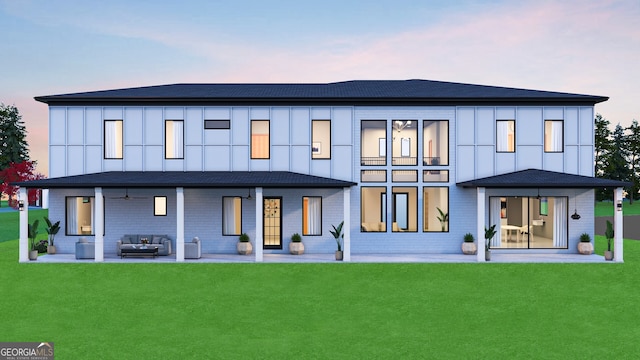 back of house with a lawn, outdoor lounge area, board and batten siding, and a patio