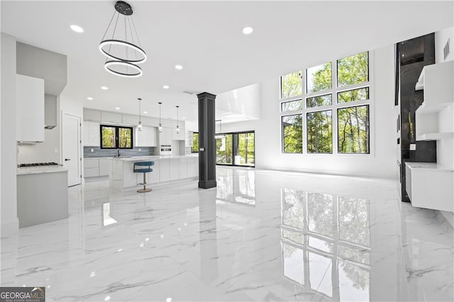 living room featuring light marble finish flooring, recessed lighting, and ornate columns
