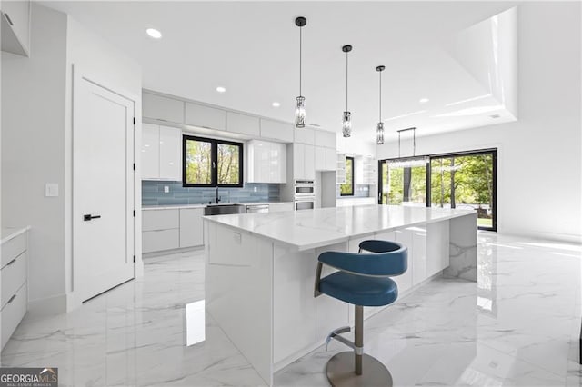kitchen with modern cabinets, light marble finish floors, white cabinetry, a sink, and recessed lighting