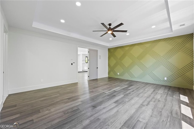 unfurnished living room featuring a tray ceiling, recessed lighting, ceiling fan, wood finished floors, and baseboards