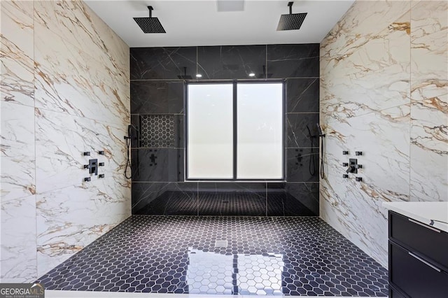 full bath featuring a tile shower, vanity, and tile walls
