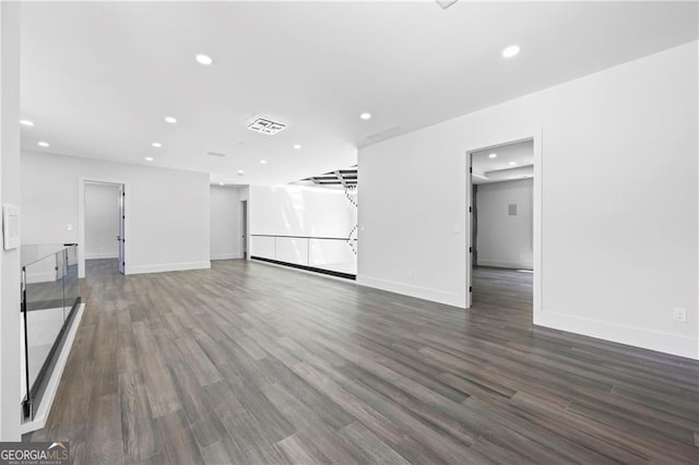 unfurnished living room with recessed lighting, dark wood-type flooring, and baseboards