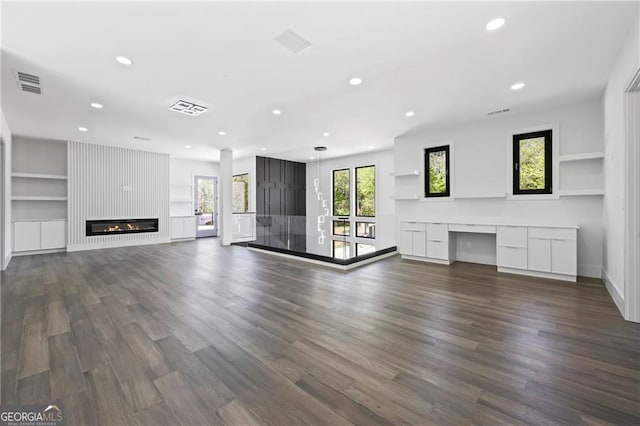 unfurnished living room featuring recessed lighting, dark wood-style flooring, a large fireplace, built in features, and baseboards