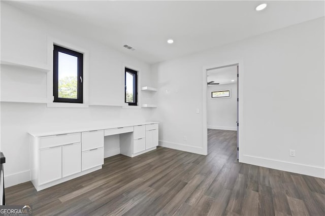 unfurnished office featuring built in desk, plenty of natural light, recessed lighting, dark wood-style flooring, and baseboards