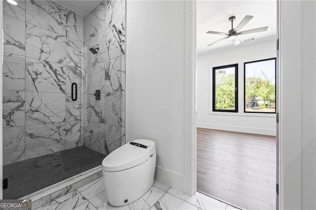 full bath with a marble finish shower, marble look tile flooring, toilet, baseboards, and ceiling fan