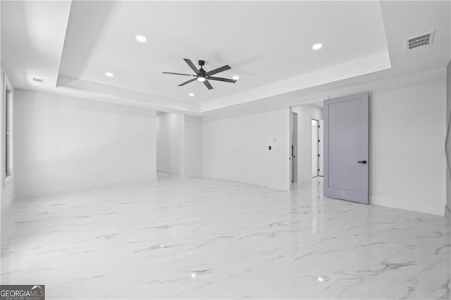 spare room with a tray ceiling, recessed lighting, a ceiling fan, baseboards, and light marble finish flooring