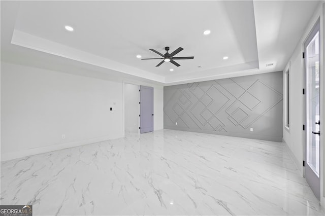 empty room with a tray ceiling, a ceiling fan, recessed lighting, and baseboards