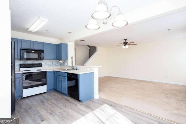 kitchen with blue cabinetry, light countertops, hanging light fixtures, open floor plan, and black appliances