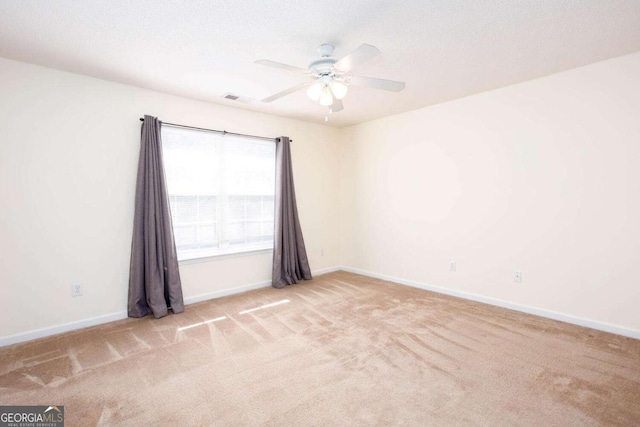 spare room with a ceiling fan, light carpet, visible vents, and baseboards