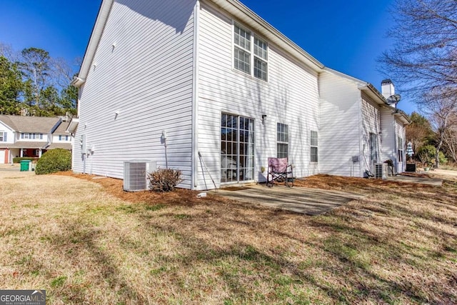 view of side of home featuring a chimney, central AC unit, a lawn, and a patio area