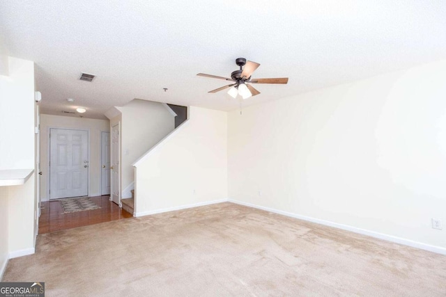 spare room with baseboards, stairs, visible vents, and light colored carpet