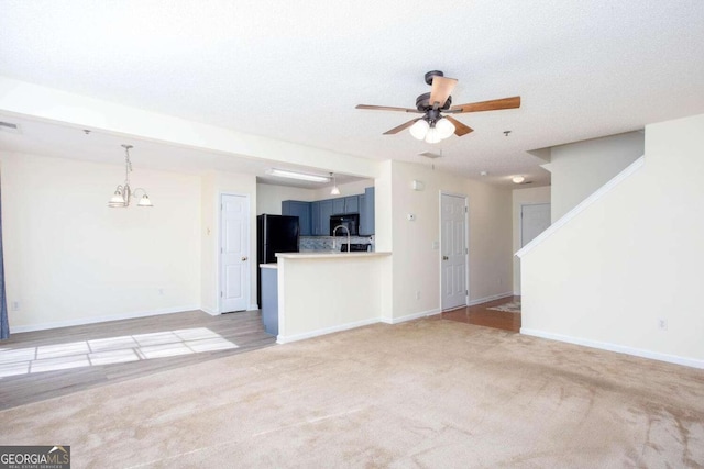 unfurnished living room with light carpet, ceiling fan, and baseboards