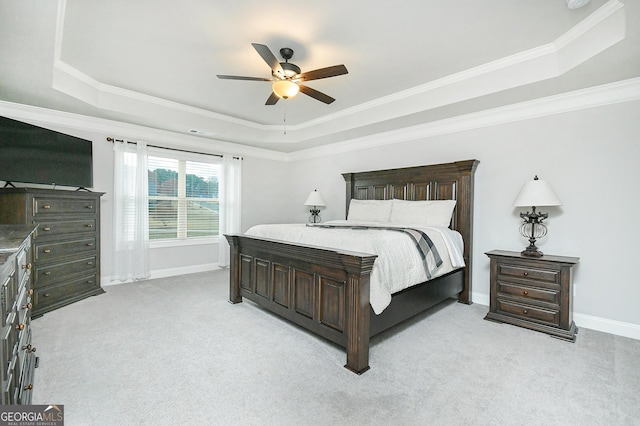 bedroom with baseboards, a tray ceiling, and light colored carpet