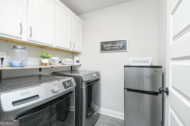 clothes washing area featuring washing machine and dryer, cabinet space, dark tile patterned floors, and baseboards