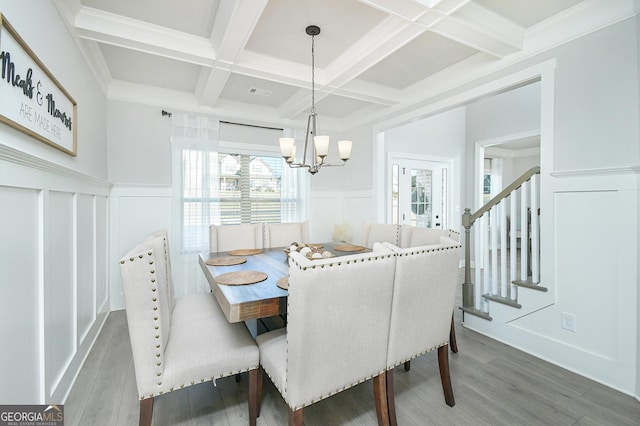 dining area featuring a notable chandelier, dark wood-type flooring, coffered ceiling, stairway, and beam ceiling