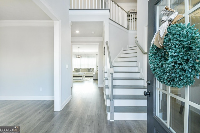 foyer entrance featuring stairs, baseboards, crown molding, and wood finished floors